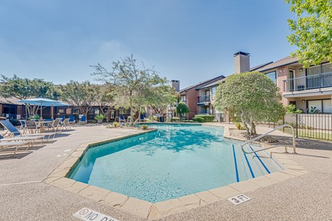 A pool surrounded by a fence and chairs.