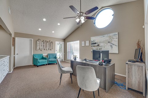 A room with a ceiling fan and a desk with a computer.