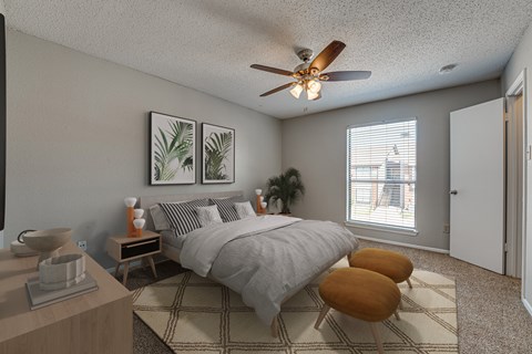 A bedroom with a bed, two chairs, and a ceiling fan.