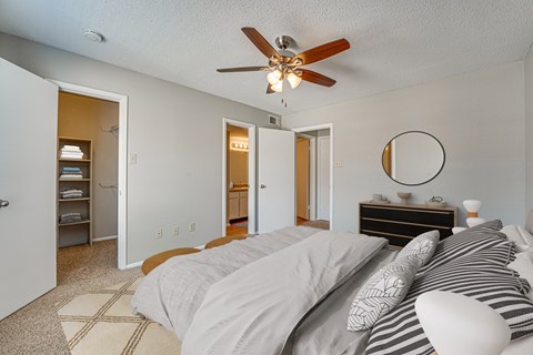 A bedroom with a bed, dresser, and a ceiling fan.