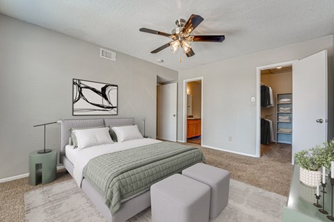 A bedroom with a bed, nightstand, and a ceiling fan.