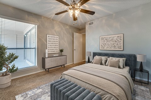 A bedroom with a large bed and a ceiling fan.