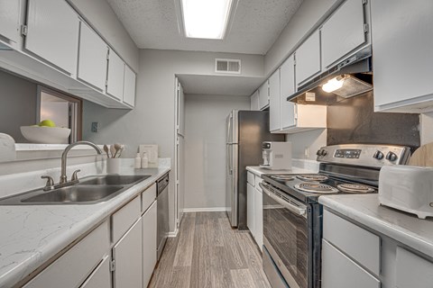 A kitchen with white cabinets and a stove top oven.