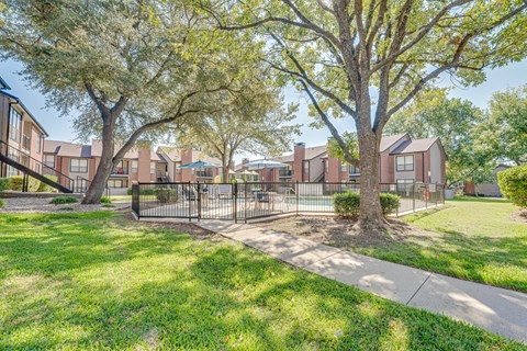 A tree in front of a building with a fence around it.