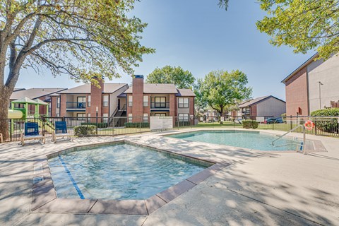 A swimming pool surrounded by a fence and trees.
