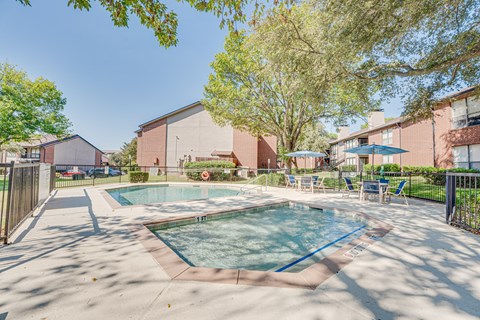 A swimming pool surrounded by trees and chairs.