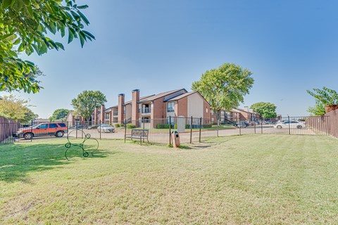 A grassy area with a playground and a building in the background.