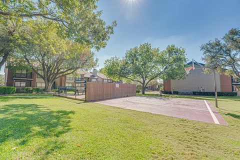 A sunny day at the park with a basketball court.