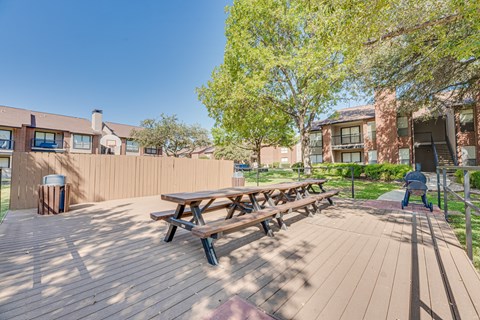 A wooden picnic table is in the middle of a wooden deck.