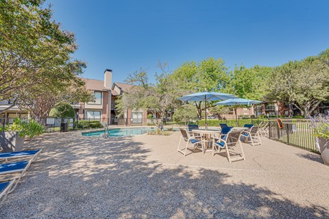 A backyard with a pool, patio furniture, and trees.