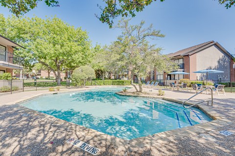 A pool surrounded by trees and chairs with a sign that says DIVING.
