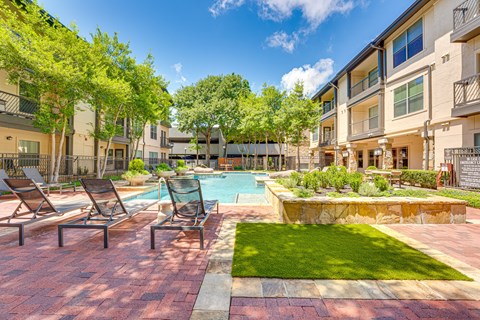 Pool deck with lounge chairs and stone water feature at The Bowen on Henderson Apartments, Dallas