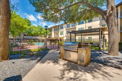 Outdoor grilling station with covered pergola and pool area at The Bowen on Henderson Apartments, Dallas, 75206