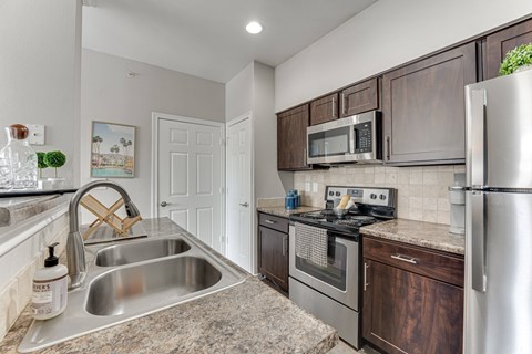 A kitchen with a stainless steel refrigerator, oven, and sink. at The Brazos, Dallas, 75287