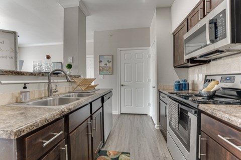 A kitchen with a sink, stove, and microwave. at The Brazos, Dallas, TX, 75287