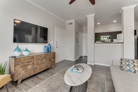 A living room with a white ceiling fan and a flat screen TV mounted on the wall. at The Brazos, Texas, 75287