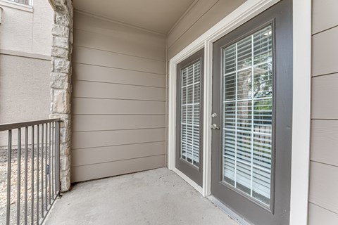 A balcony with a sliding glass door and a metal railing. at The Brazos, Dallas, 75287