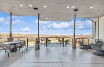 A patio with a table and chairs overlooking a field.