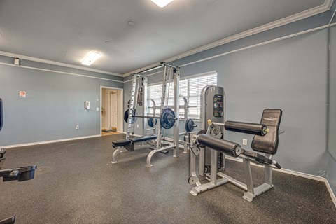 A gym with a variety of equipment including a leg press machine and a bench press.