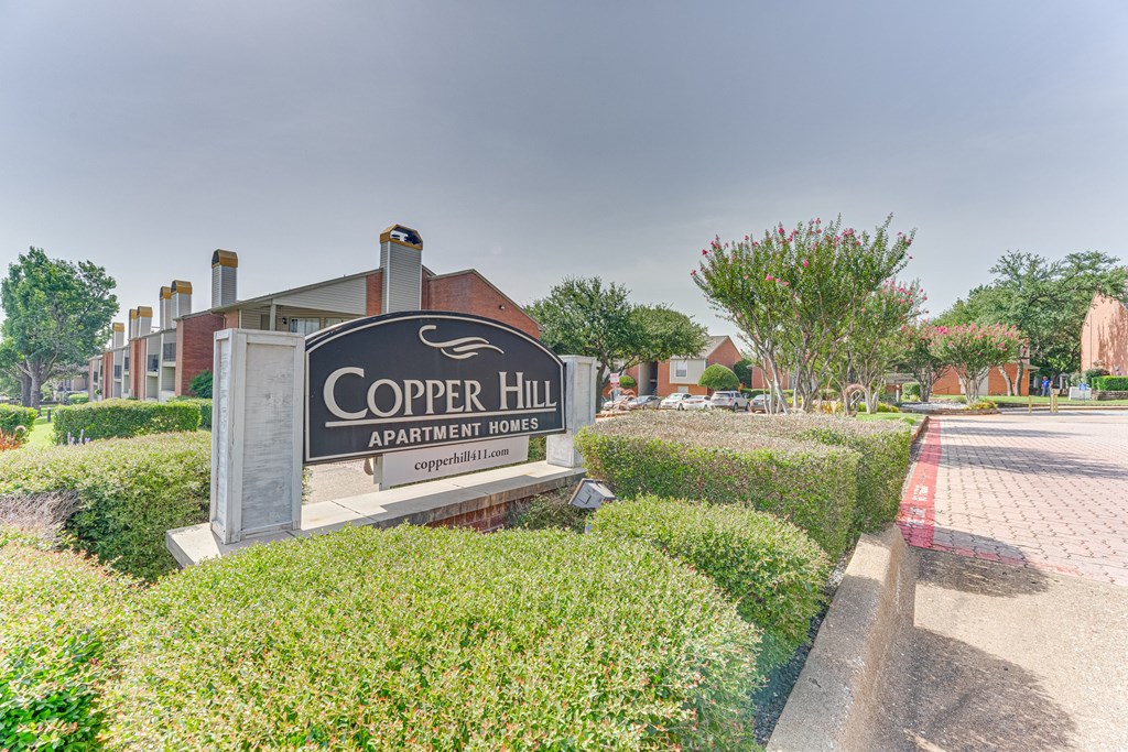 A sign for Copper Hill Apartment Homes is in front of a building at Copper Hill Apartments, Bedford, TX