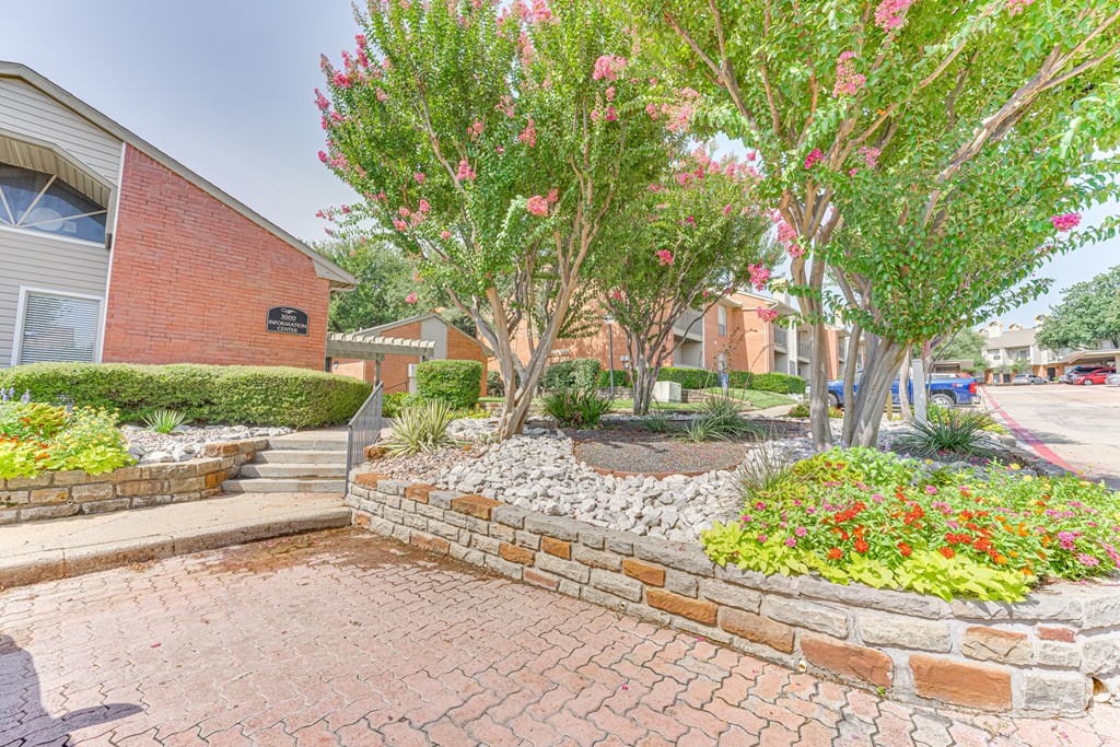 A brick wall with a flower bed in front of a building at Copper Hill Apartments, Bedford 76021