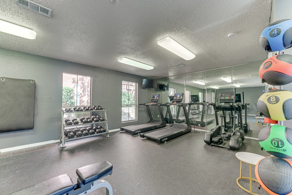 A gym with a variety of equipment including treadmills, weights, and exercise machines at Copper Hill Apartments, Bedford 76021
