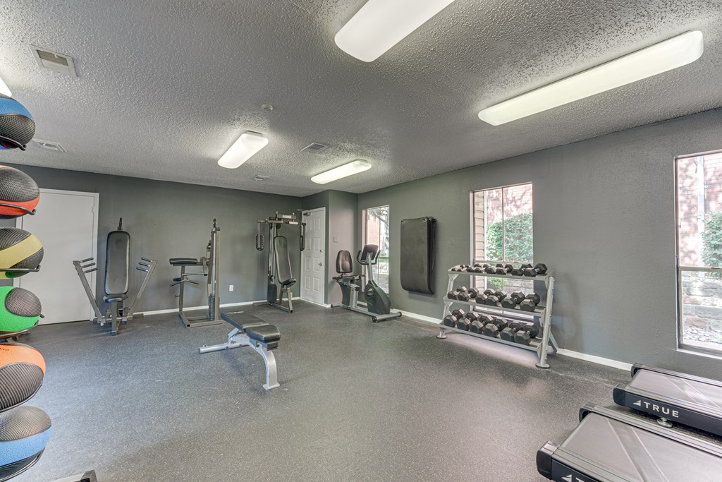 A well-equipped gym with a variety of exercise machines and weights at Copper Hill Apartments, Bedford, Texas