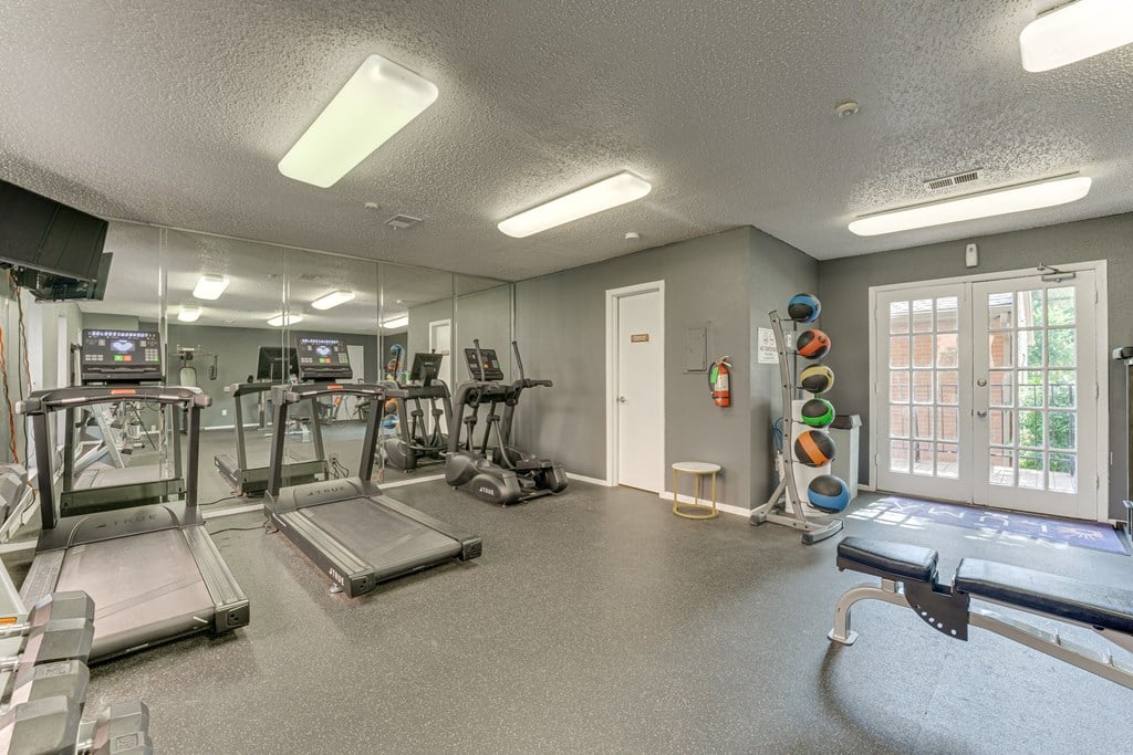 A gym with treadmills, exercise equipment, and a mirrored wall at Copper Hill Apartments, Texas, 76021