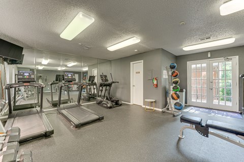 A gym with treadmills, exercise equipment, and a mirrored wall.