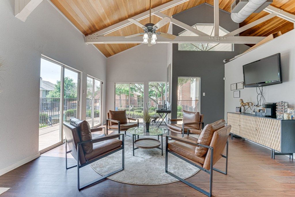 A living room with brown leather chairs and a glass table at Copper Hill Apartments, Bedford, TX