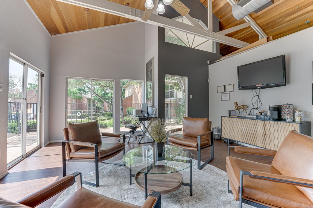 A modern living room with brown leather chairs and a glass coffee table at Copper Hill Apartments, Bedford, TX, 76021