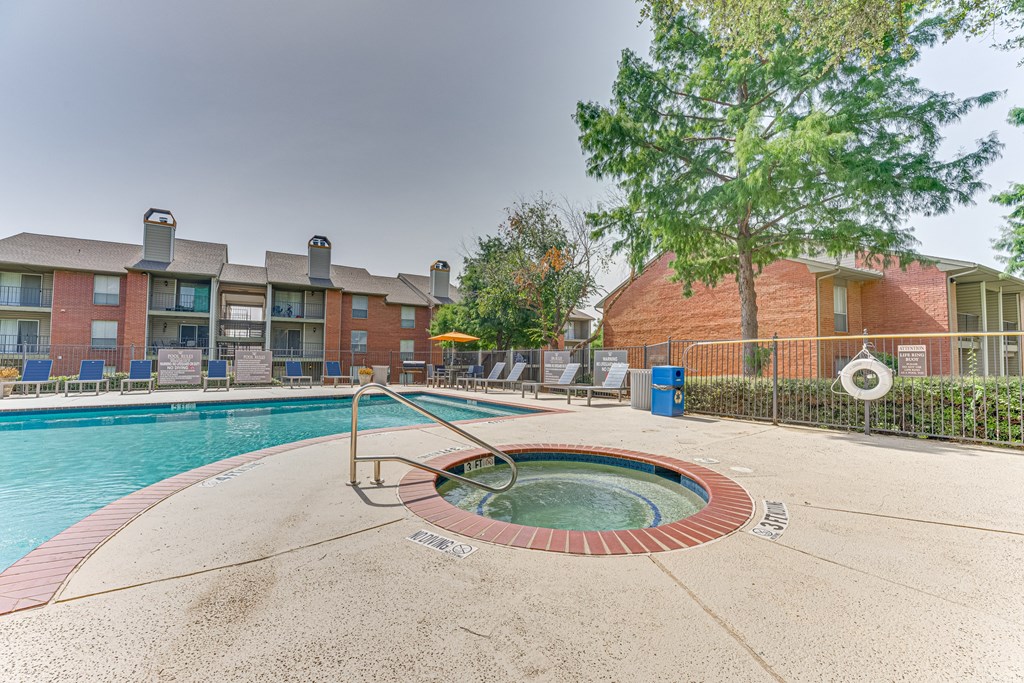 A swimming pool with a hot tub in the middle of it at Copper Hill Apartments, Texas