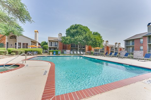 A large swimming pool surrounded by a red brick border.