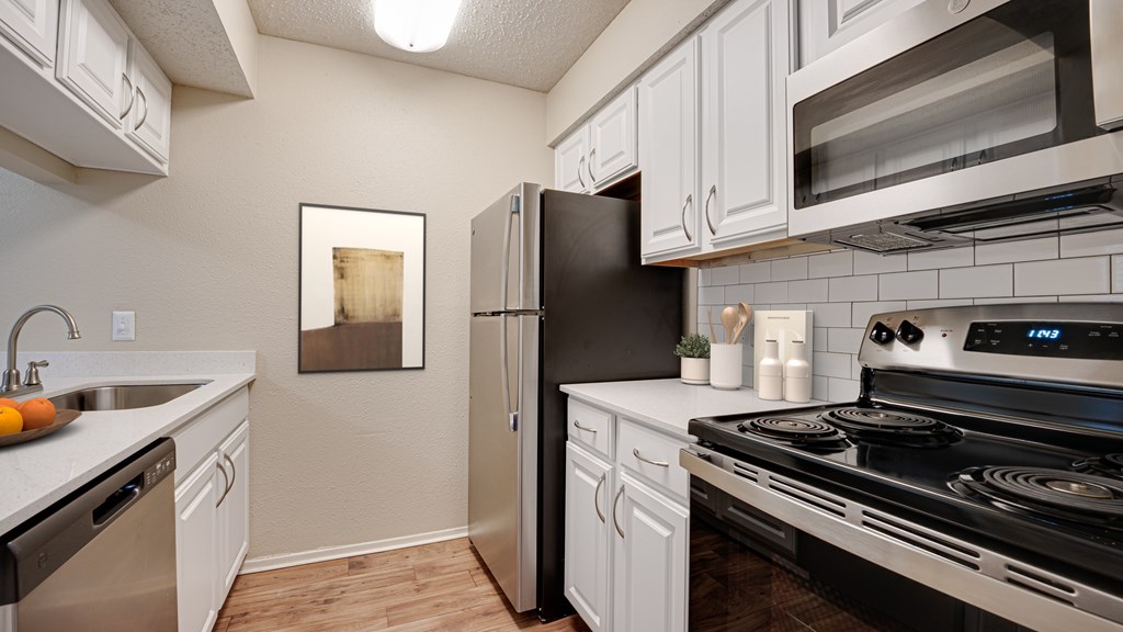 A modern kitchen with black appliances and white cabinets at Copper Hill Apartments, Bedford, TX, 76021