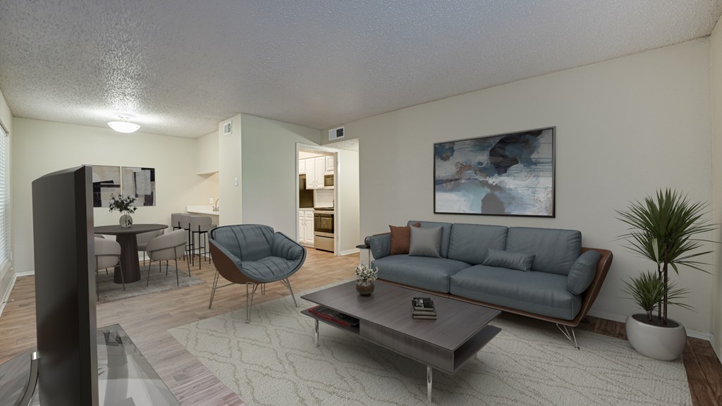 A living room with a grey couch, a chair, a coffee table, and a painting on the wall at Copper Hill Apartments, Bedford, Texas