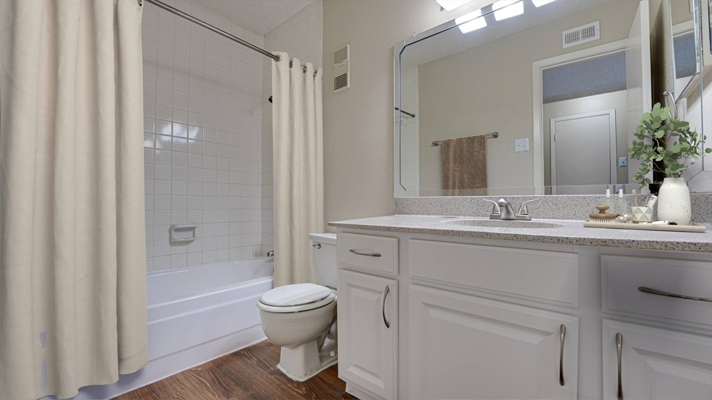 A white bathroom with a toilet, sink, and shower at Copper Hill Apartments, Texas