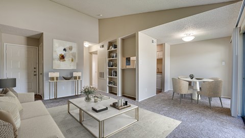 A living room with a white sofa, a coffee table, and a dining table with chairs.