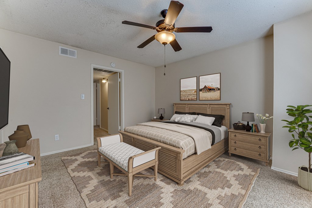 A bedroom with a bed, a bench, and a ceiling fan.
