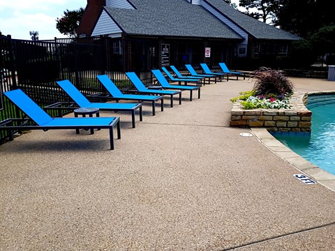 A poolside area with blue lounge chairs and a pool.