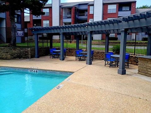 A pool with a blue bench and a black fence.