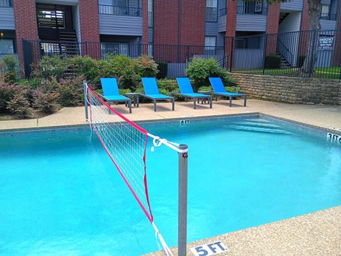 A pool with a red net in front of a brick building.