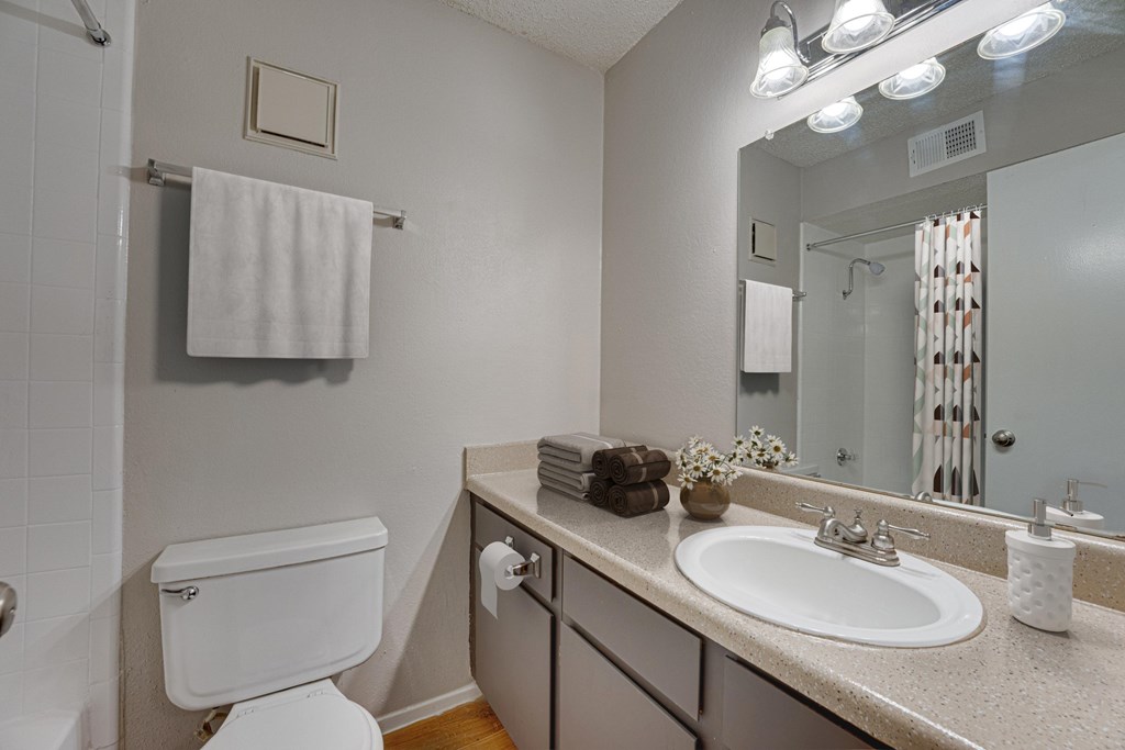 A white toilet is next to a sink in a bathroom at Indian Creek Apartments, Texas