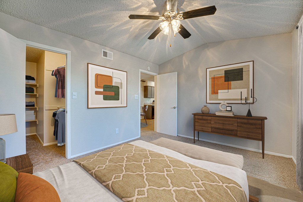 A bedroom with a bed, dresser, and mirror at Indian Creek Apartments, Carrollton, Texas