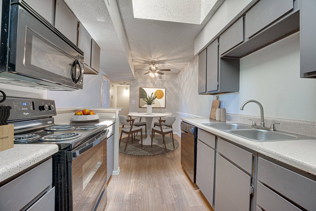 A kitchen with a stove top oven and a microwave at Indian Creek Apartments, Carrollton 75007