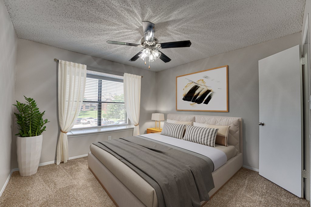 A bedroom with a bed, a ceiling fan, and a painting on the wall at Indian Creek Apartments, Texas