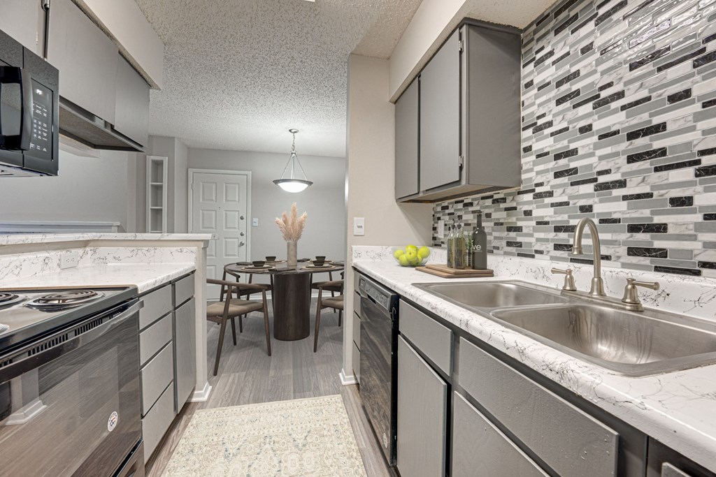 A kitchen with a dining table and chairs in the middle at Indian Creek Apartments, Carrollton 75007