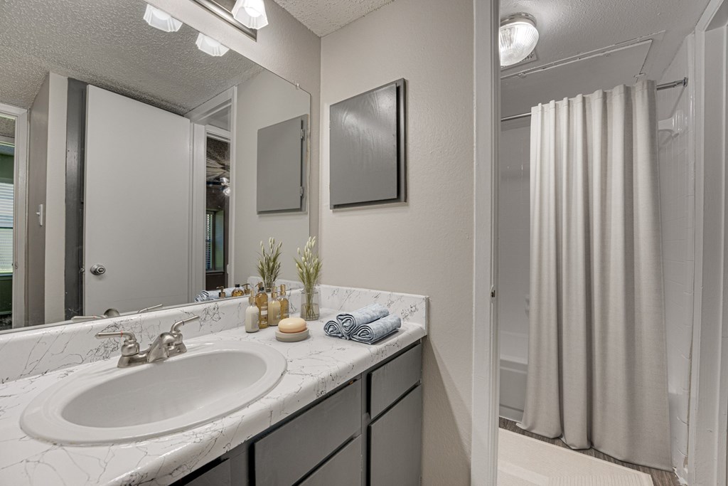 A bathroom with a white sink and a mirror at Indian Creek Apartments, Carrollton, Texas