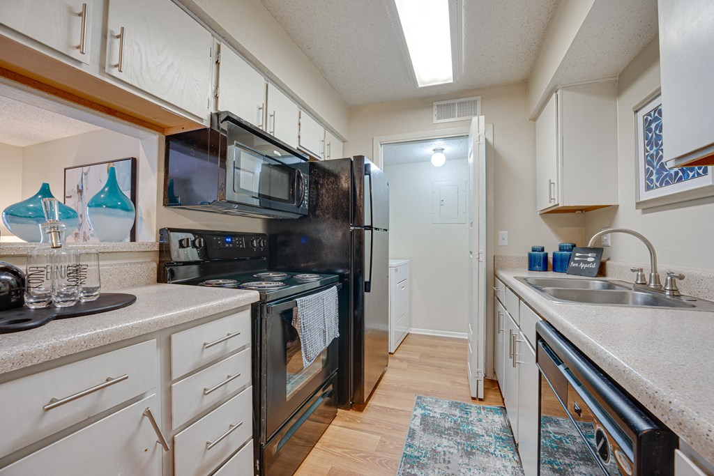 a kitchen with black appliances and white cabinets at Indian Creek Apartments, Texas