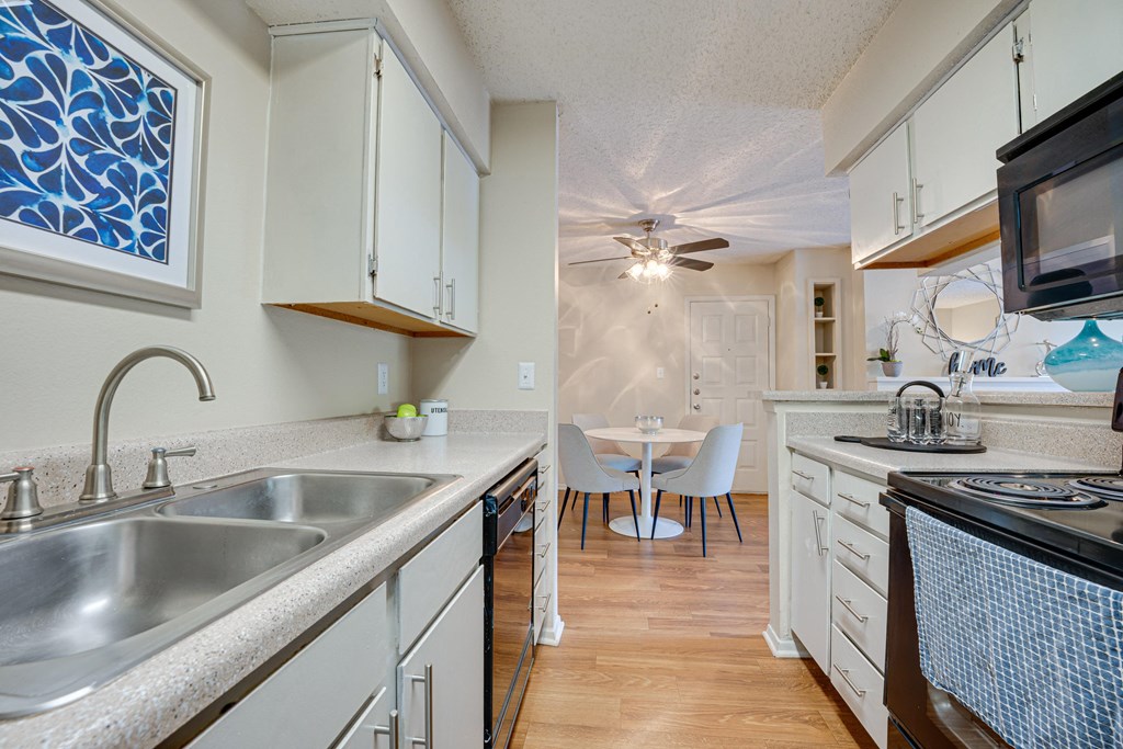 a kitchen with a sink and a stove and a dining room at Indian Creek Apartments, Carrollton, TX