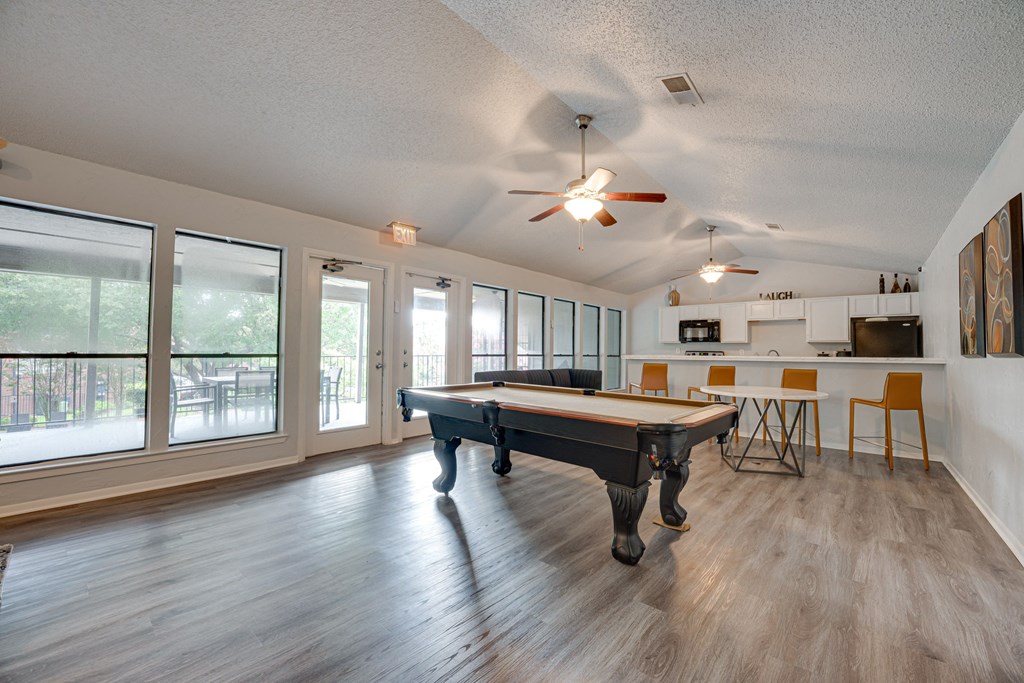 an open living room with a pool table and a kitchen with windows at Indian Creek Apartments, Carrollton, TX, 75007
